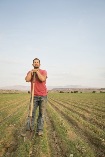 Caucasian farmer with shovel in crop field