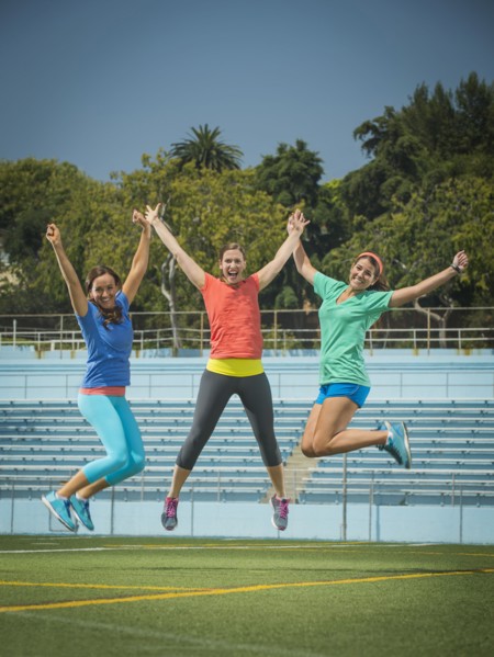 Caucasian women jumping for joy in stadium field