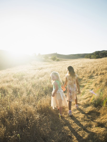 Caucasian girls holding hands in rural field