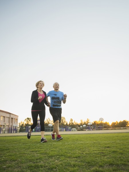 Older couple jogging together in urban park