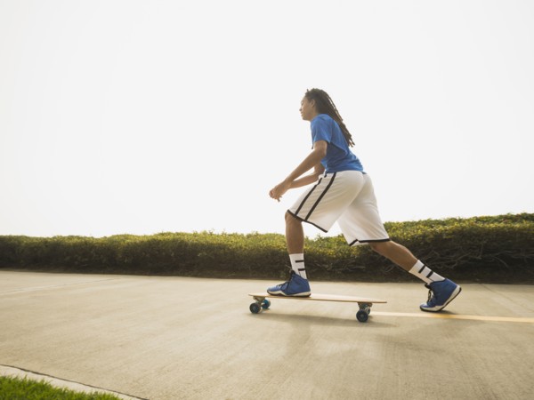 Black teenage boy riding skateboard on street