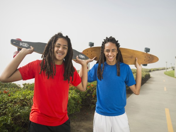 Black teenage boys carrying skateboards on street