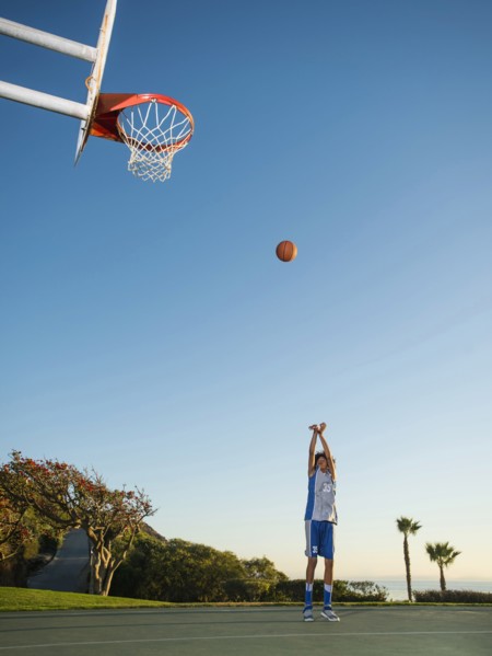 Black teenage boy shooting basketball on court