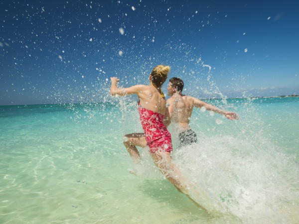 Caucasian couple splashing in waves in tropical ocean