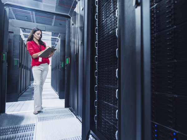 Caucasian businesswoman reading clipboard in server room