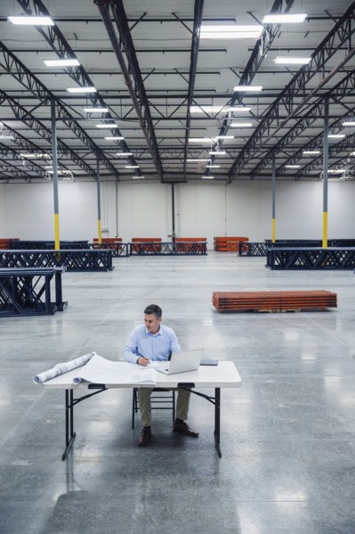 Caucasian architect reading blueprints in warehouse