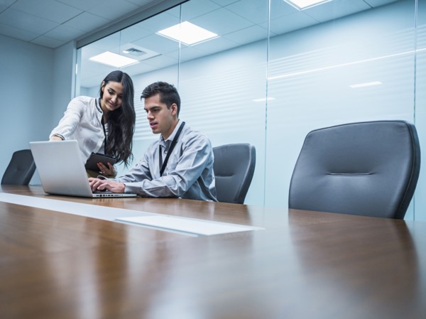 Business people using laptop in conference room