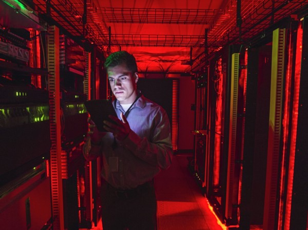 Hispanic technician using digital tablet in server room