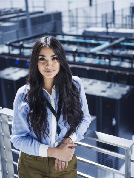 Mixed race businesswoman smiling on balcony over server room