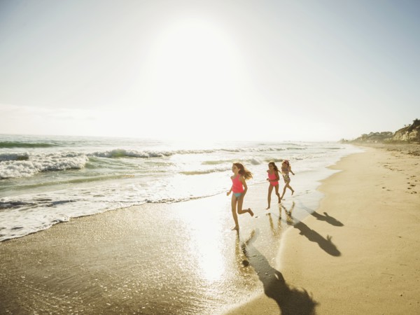Caucasian sisters running on beach