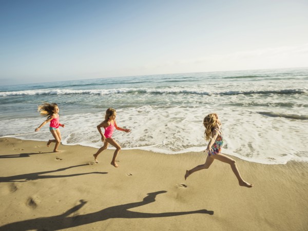 Caucasian sisters running on beach