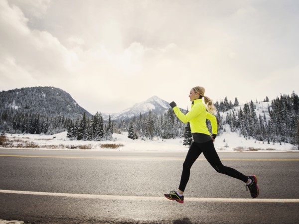 Caucasian woman running on snowy road