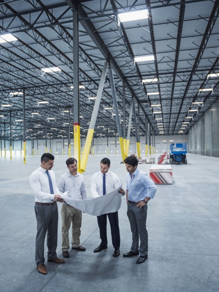 Architects examining blueprint in empty warehouse