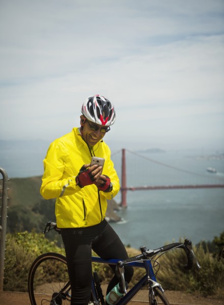 Hispanic man on bicycle texting on cell phone at waterfront