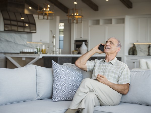Caucasian man sitting on sofa talking on cell phone