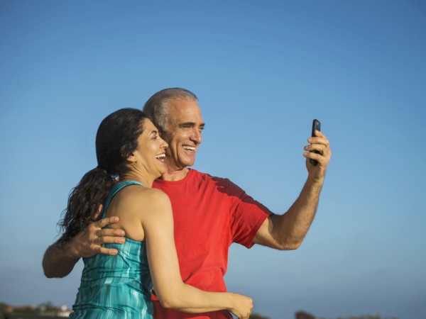 Older couple laughing and posing for cell phone selfie