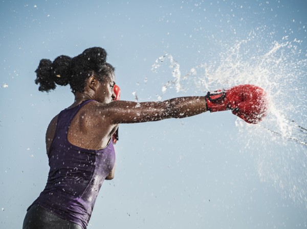 Water spraying on black woman boxing
