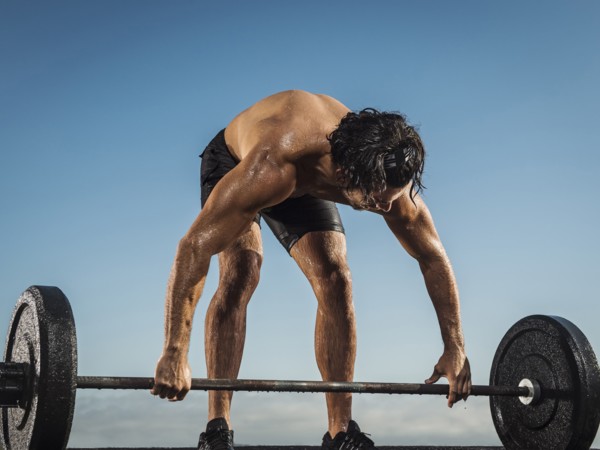 Sweating Hispanic man lifting barbell