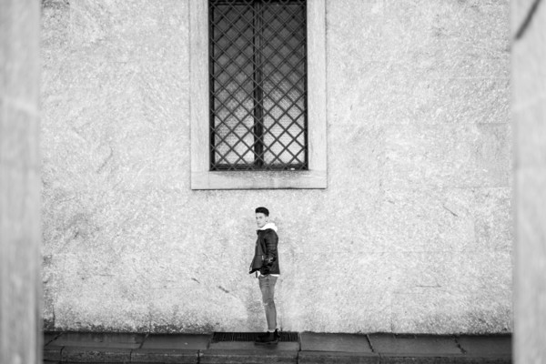 Portrait of distant man standing underneath window on sidewalk