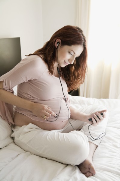 Pregnant Hispanic woman playing music for unborn baby