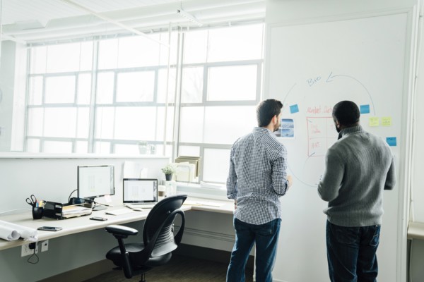 Businessmen using whiteboard in office