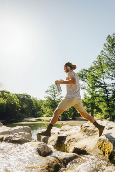 Caucasian man jumping on rocks near river