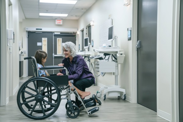 Smiling doctor comforting girl in wheelchair