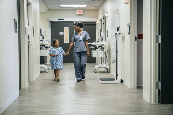 Nurse holding hands with girl in hospital