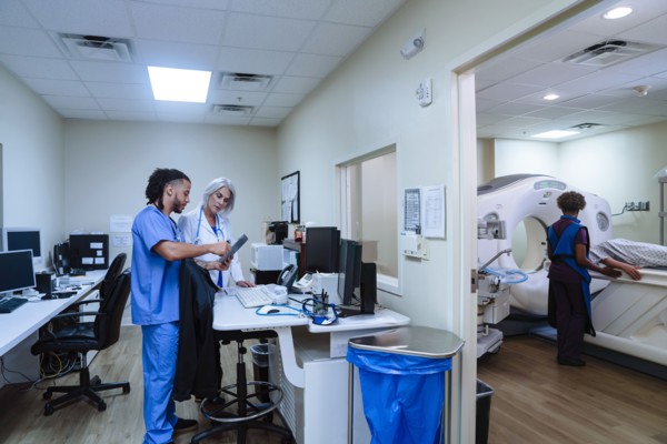 Doctor and nurse discussing digital tablet near scanner