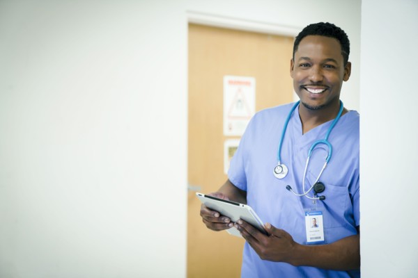 Portrait of smiling black nurse holding digital tablet
