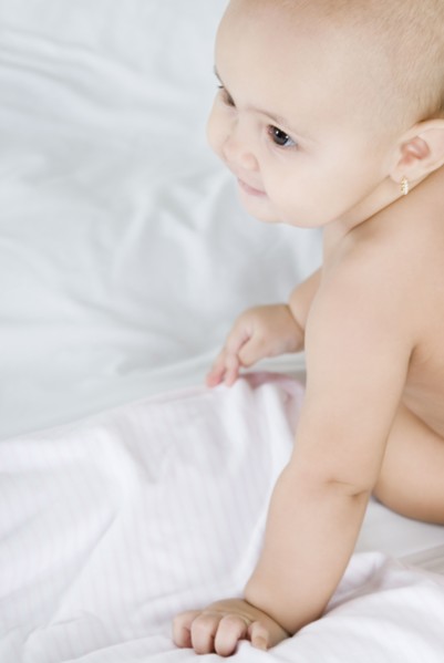 Hispanic baby sitting on bed