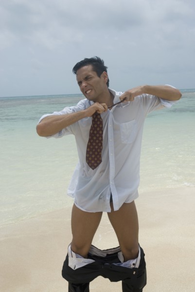 Hispanic businessman stripping at beach