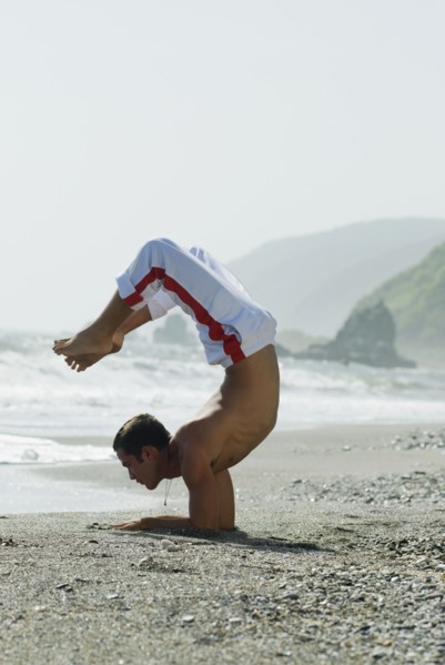 Hispanic man doing yoga at beach