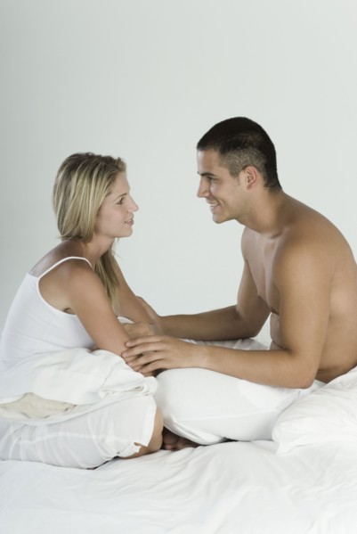 Smiling Hispanic couple sitting in bed