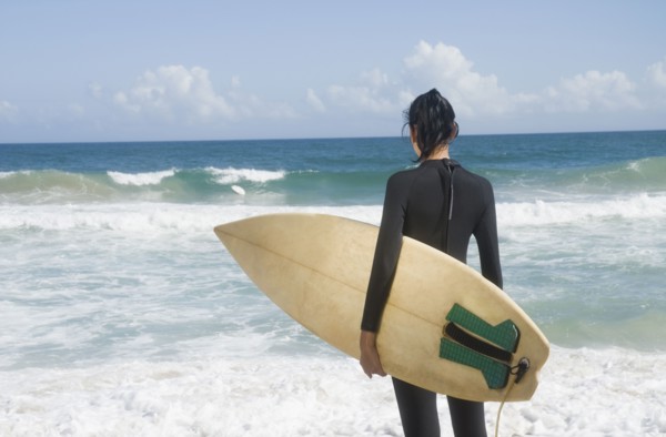 Hispanic woman at beach with surfboard