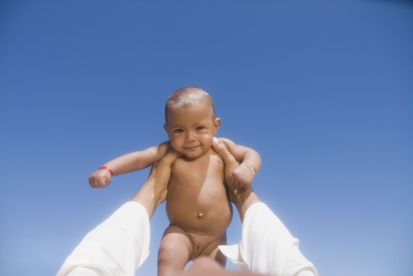 African man lifting nude baby girl