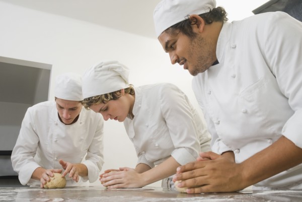 Bakers working with dough in bakery kitchen