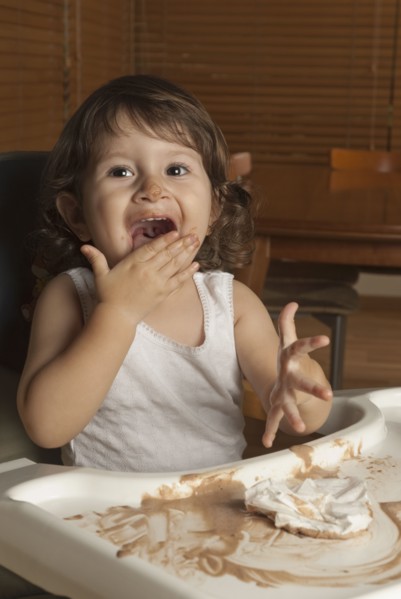 Hispanic baby in high chair licking hand
