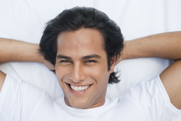 Smiling Hispanic man laying in bed