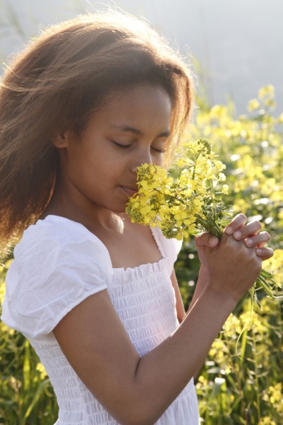 Mixed race girl smelling flowers