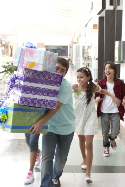 Hispanic friends carrying gifts in shopping mall