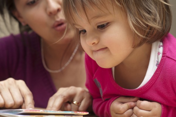 Hispanic mother reading book to daughter