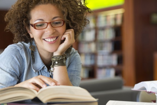 Hispanic woman reading book in library