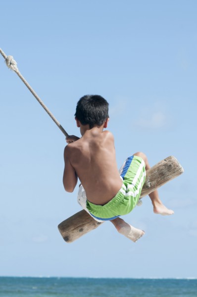 Hispanic boy playing on swing outdoors