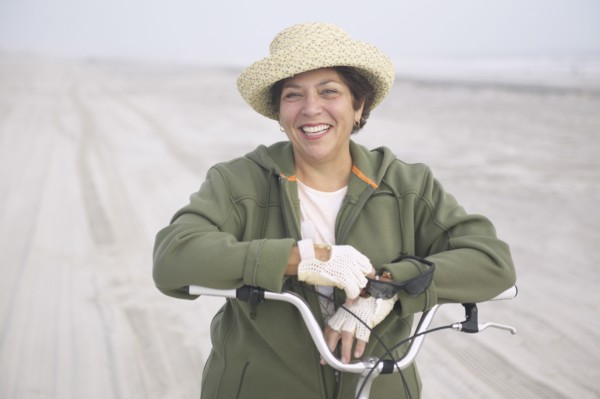 Senior woman with bicycle on beach