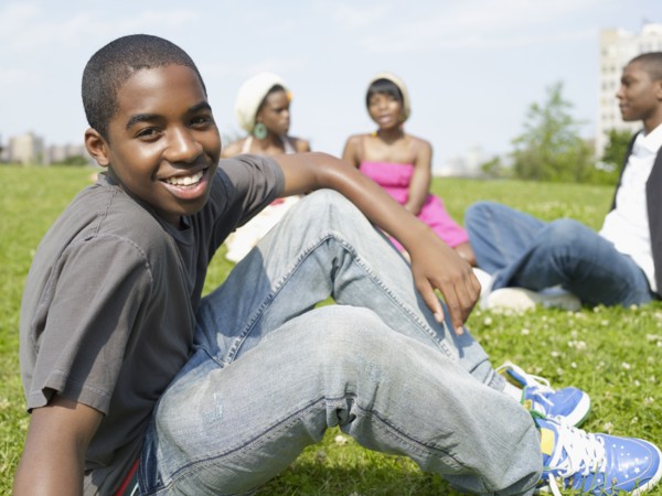 Confident African boy sitting in park with friends
