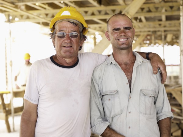 Hispanic workers hugging construction site