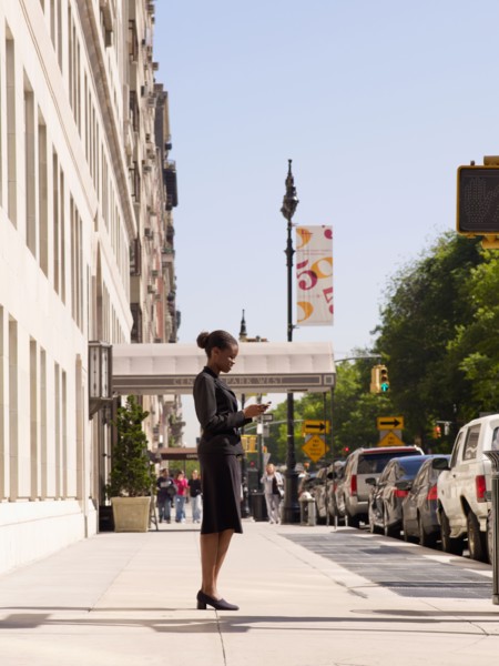 African businesswoman looking at cell phone on sidewalk