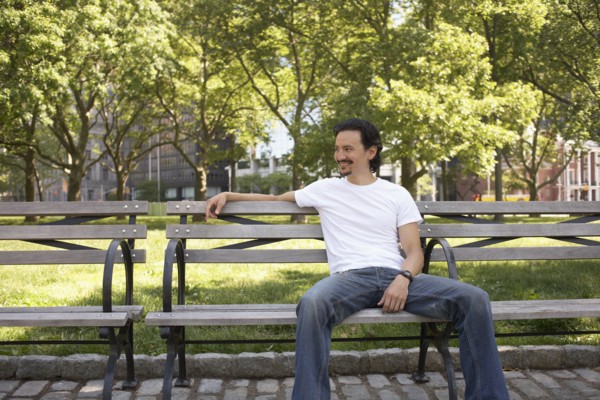Mixed race man relaxing on park bench