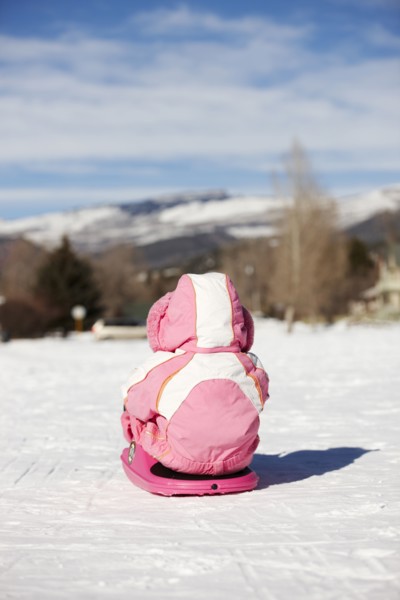 Mixed race girl sledding in snow